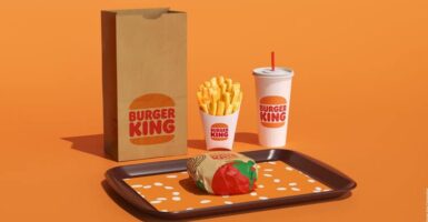 burger king burger on tray with fries cups with straws paper bag orange background