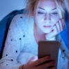 Woman in bed looking at phone