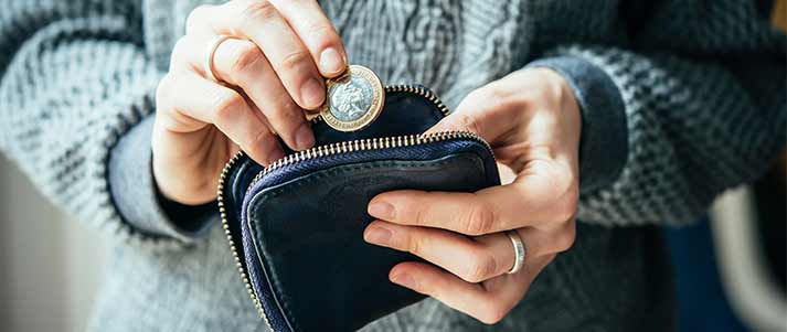 lady holding a pound coin putting into a wallet